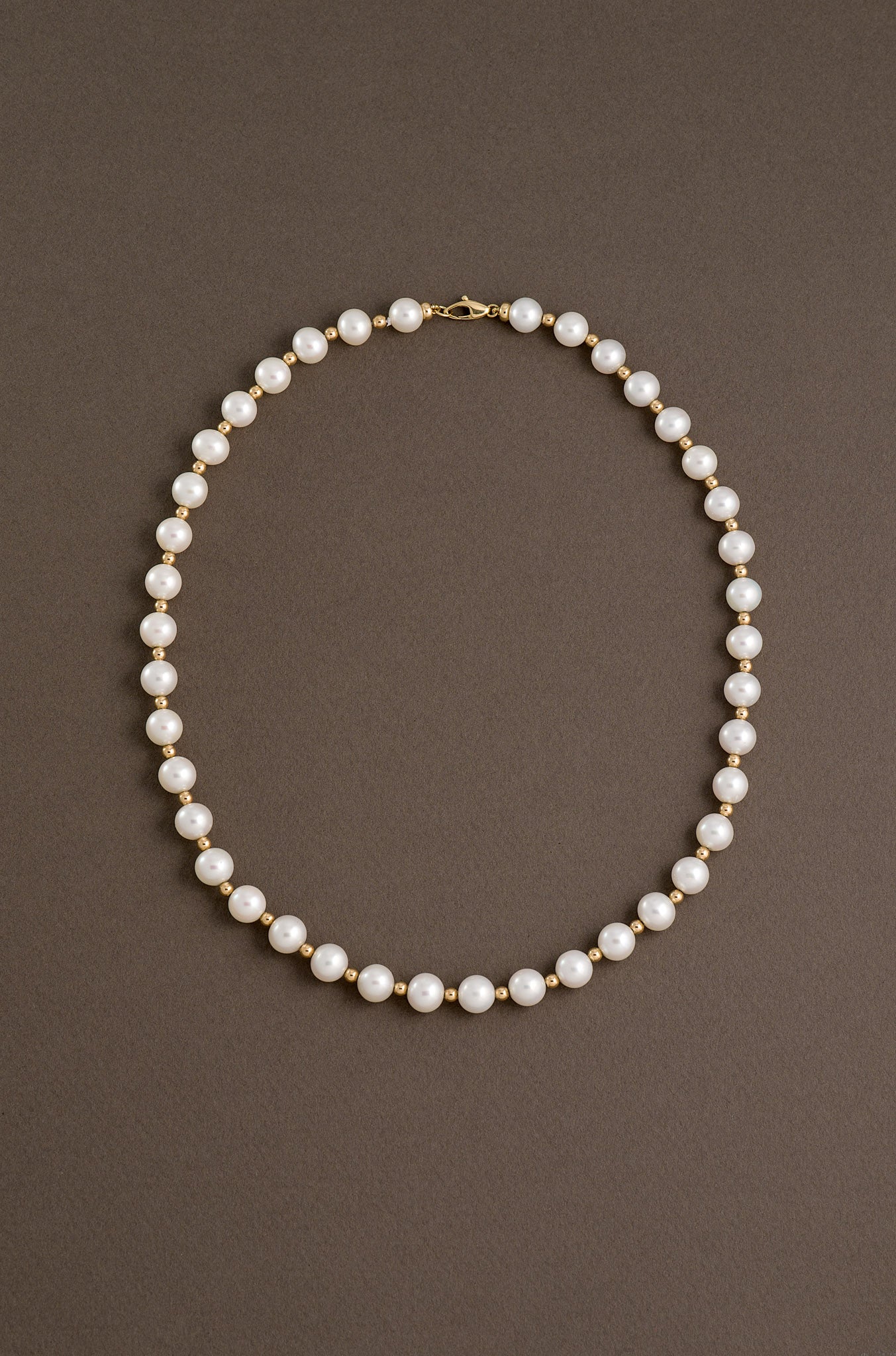 Pearl necklace WITH SOLID GOLD SPACER BEADS on a brown background